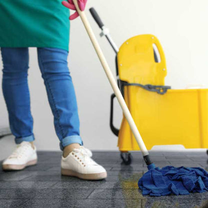 Person mopping a tile floor with mop bucket in background